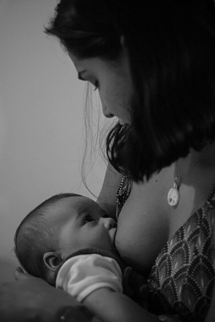 Grayscale Photo of a Woman Breastfeeding 